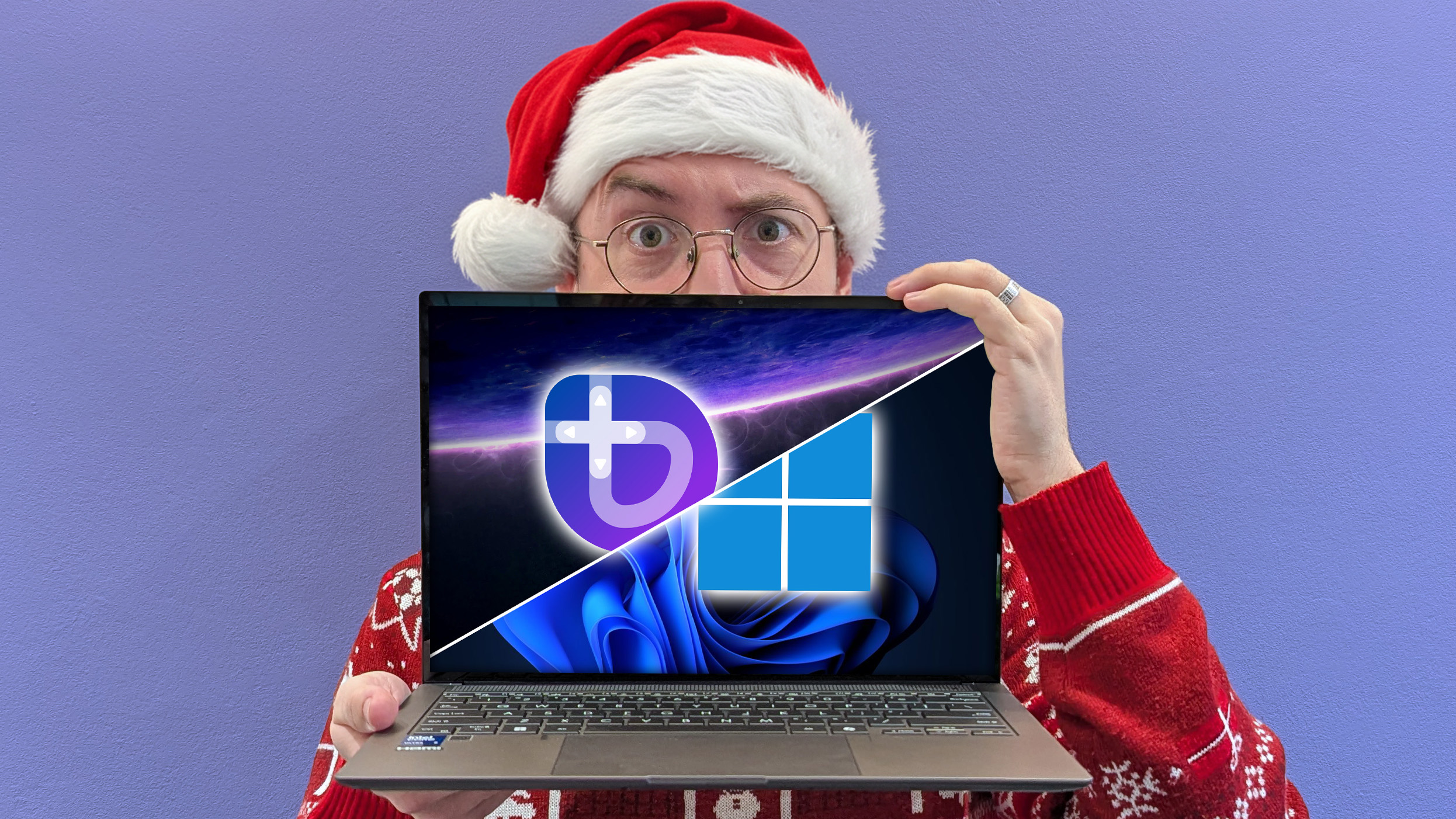 Windows Central Senior Editor Ben Wilson in a Christmas-themed hat holding an ASUS laptop with Bazzite and Windows logos appearing its screen